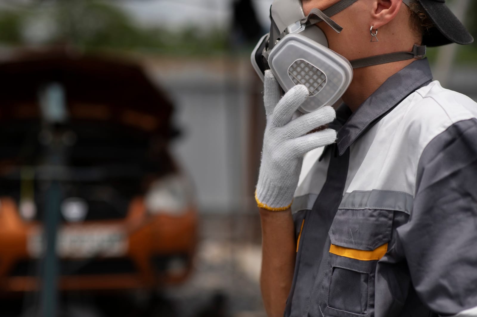 Mão com luva segurando um detector de quatro gases em frente a trabalhadores abrindo um registro de visita